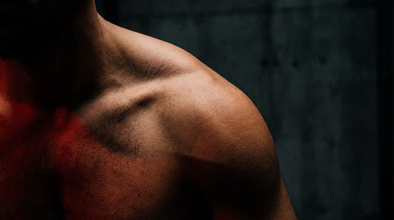 Close-up of a man's shoulder and back under raking red light